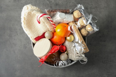 Photo of Basket with gift set and Christmas decor on grey table, top view