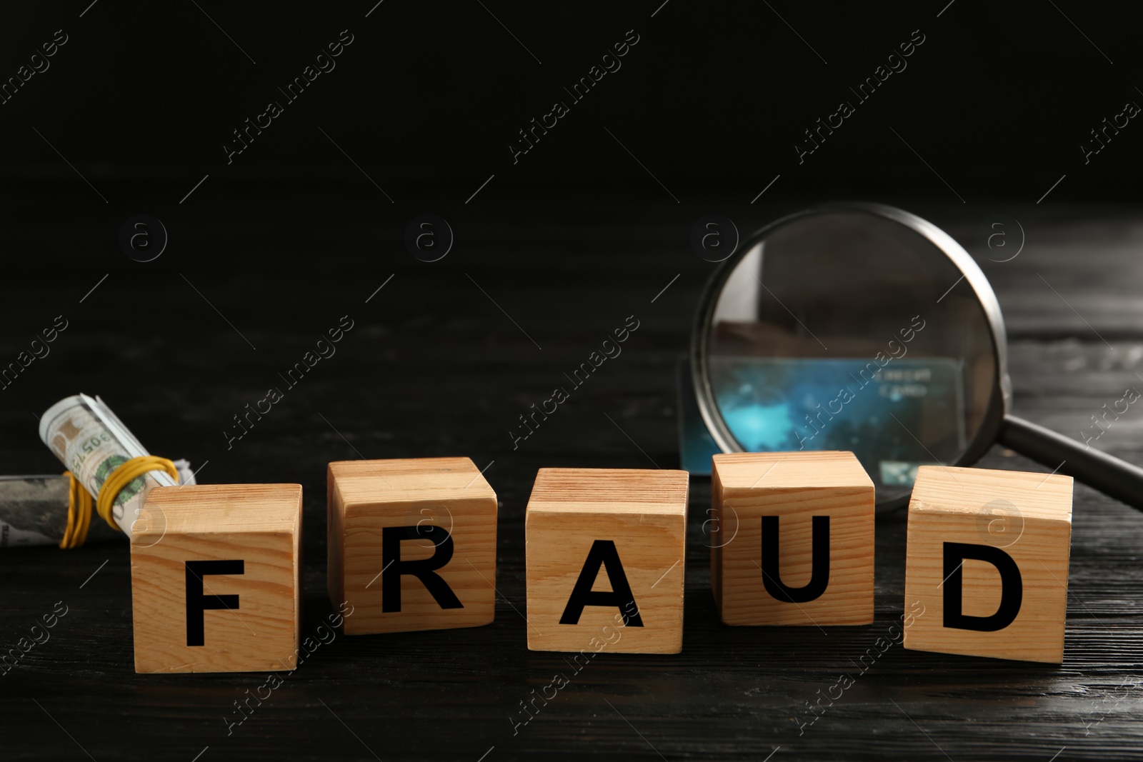 Photo of Wooden cubes with word Fraud near credit card, magnifying glass and money on black table, space for text