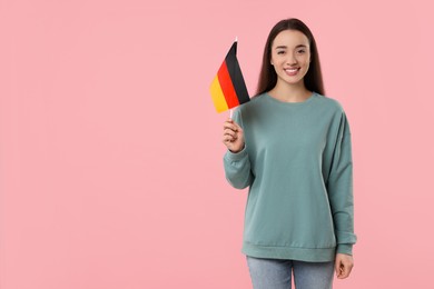 Photo of Young woman holding flag of Germany on pink background, space for text