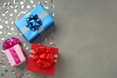 Photo of Gift boxes and shiny confetti on grey background, flat lay. Space for text