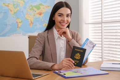 Travel agent with ticket and passport at table in office