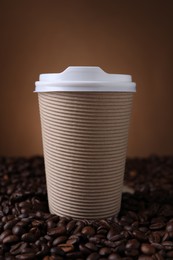 Photo of Coffee to go. Paper cup on roasted beans against brown background