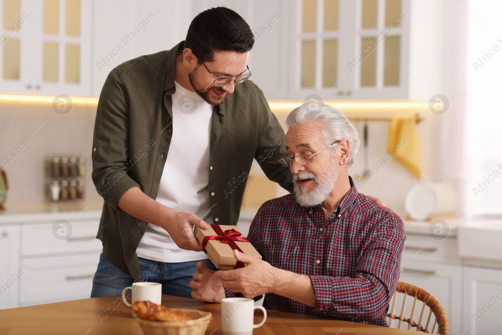 Photo of Son giving gift box to his dad at home