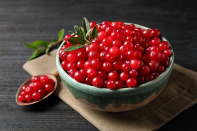 Photo of Tasty ripe cranberries on black wooden table, closeup