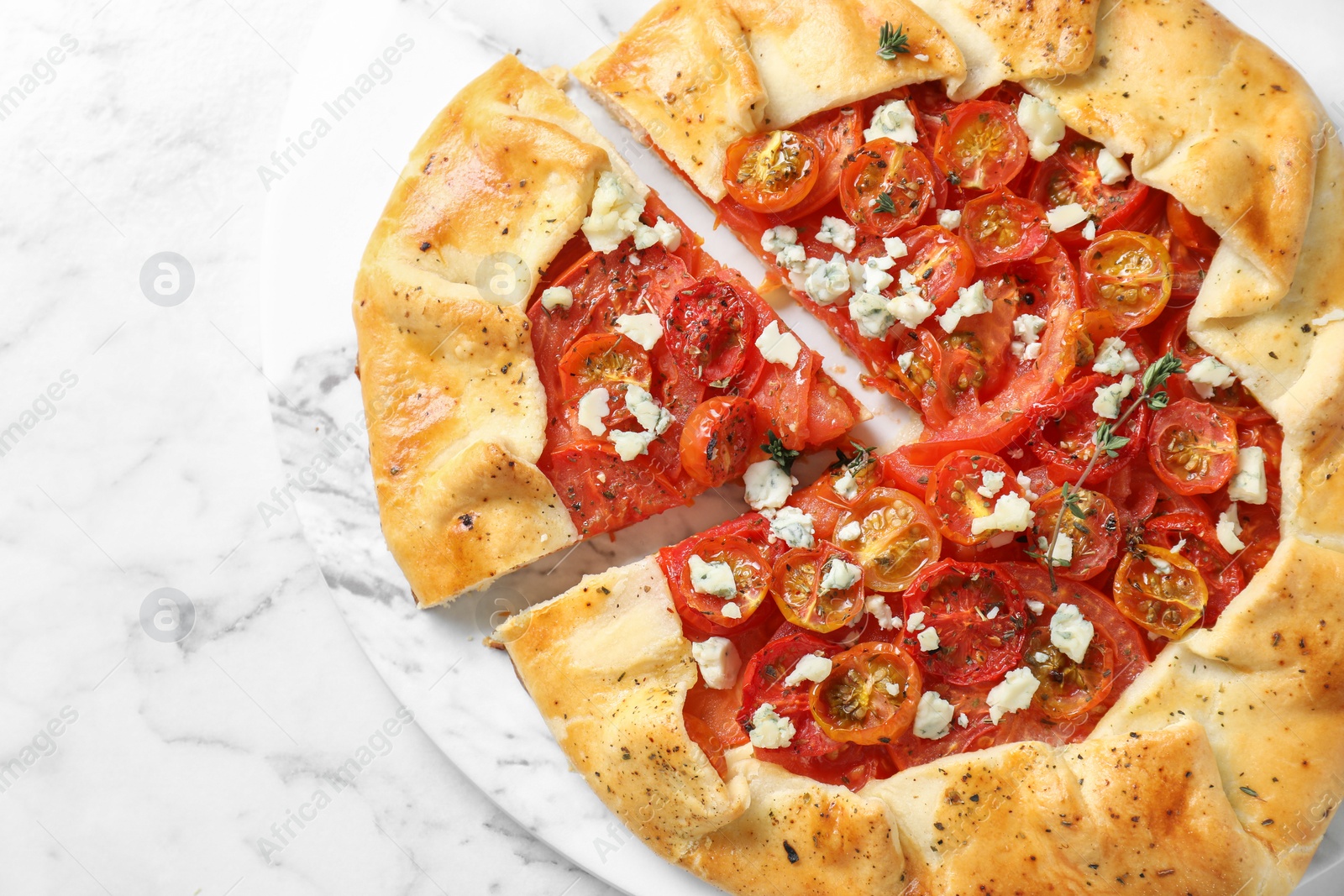 Photo of Tasty galette with tomato, thyme and cheese (Caprese galette) on white marble table, top view. Space for text