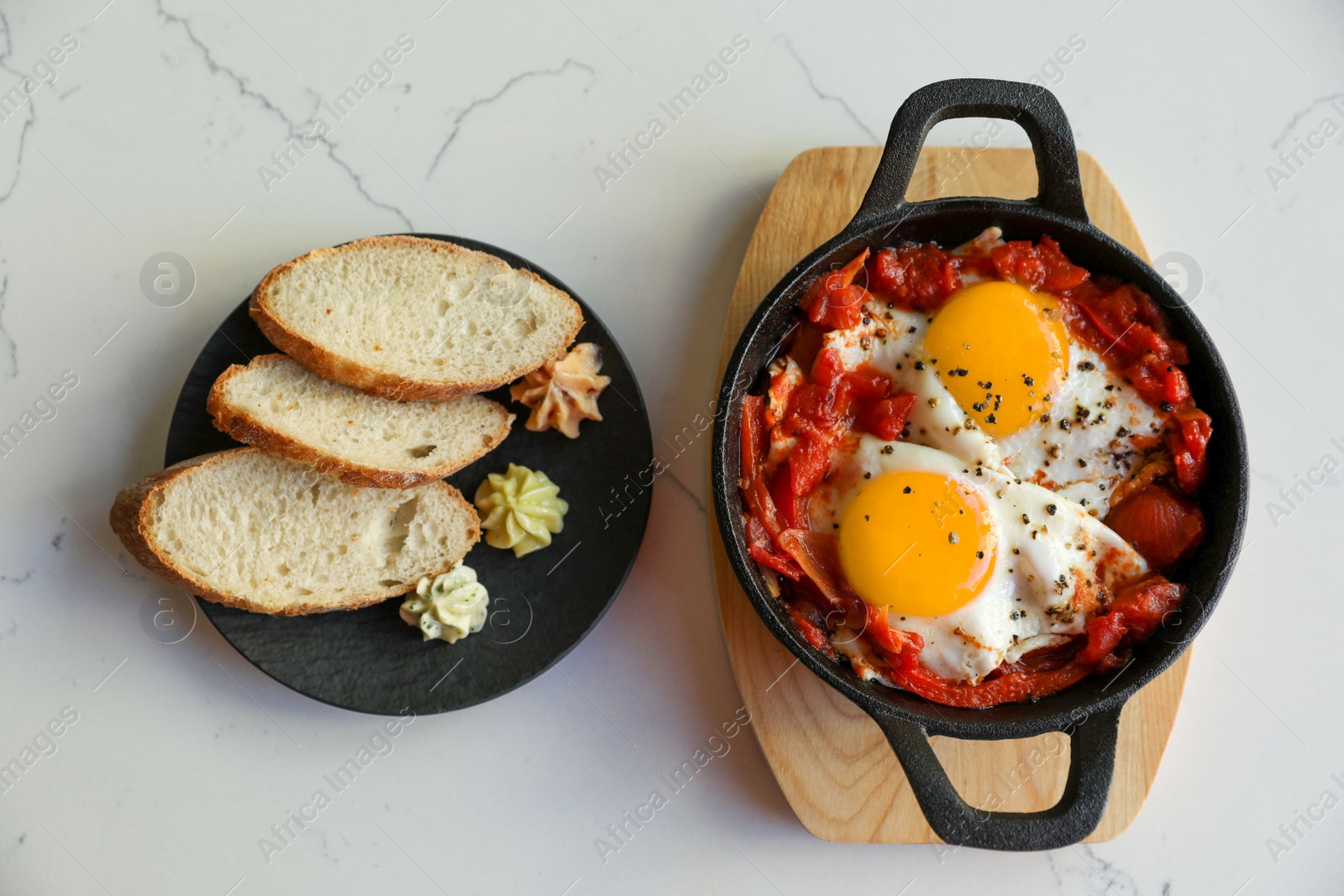 Photo of Tasty Shakshouka served on white marble table, flat lay