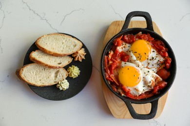 Tasty Shakshouka served on white marble table, flat lay