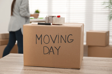 Photo of Cardboard box with words MOVING DAY and packaging items on wooden table