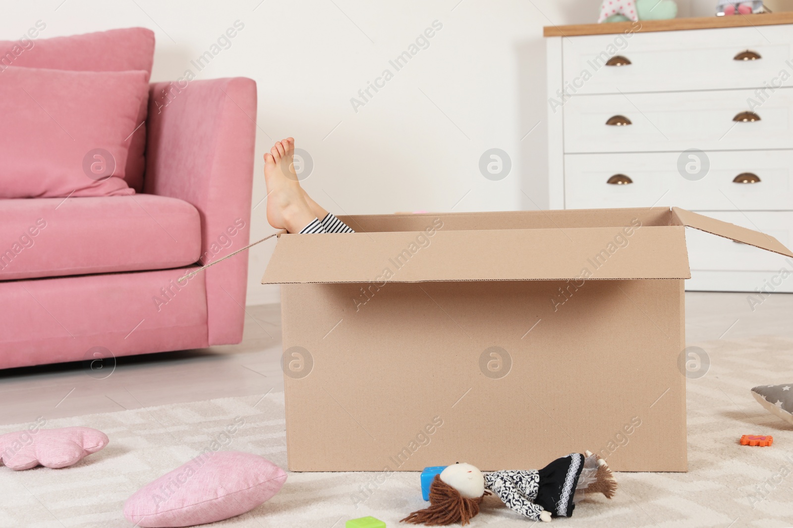 Photo of Cute little child playing with cardboard box at home