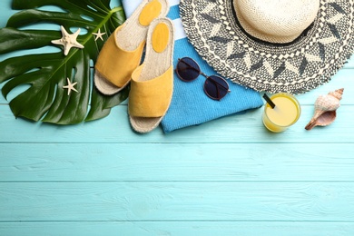 Photo of Beach accessories and drink on light blue wooden table, flat lay. Space for text