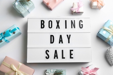 Photo of Lightbox with phrase BOXING DAY SALE and Christmas decorations on white background, flat lay