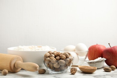 Photo of Nutmeg seeds and other ingredients for pastry on white marble table