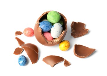 Photo of Tasty broken chocolate egg with colorful candies isolated on white