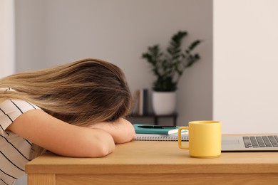 Photo of Woman sleeping in front of laptop at wooden table indoors