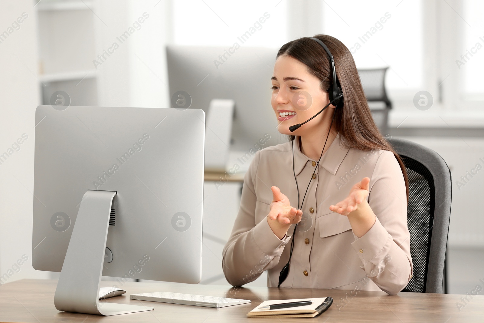 Photo of Hotline operator with headset working on computer in office