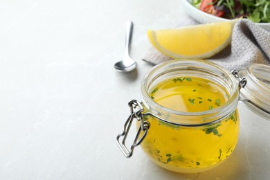 Photo of Jar with lemon sauce on light table, space for text. Delicious salad dressing