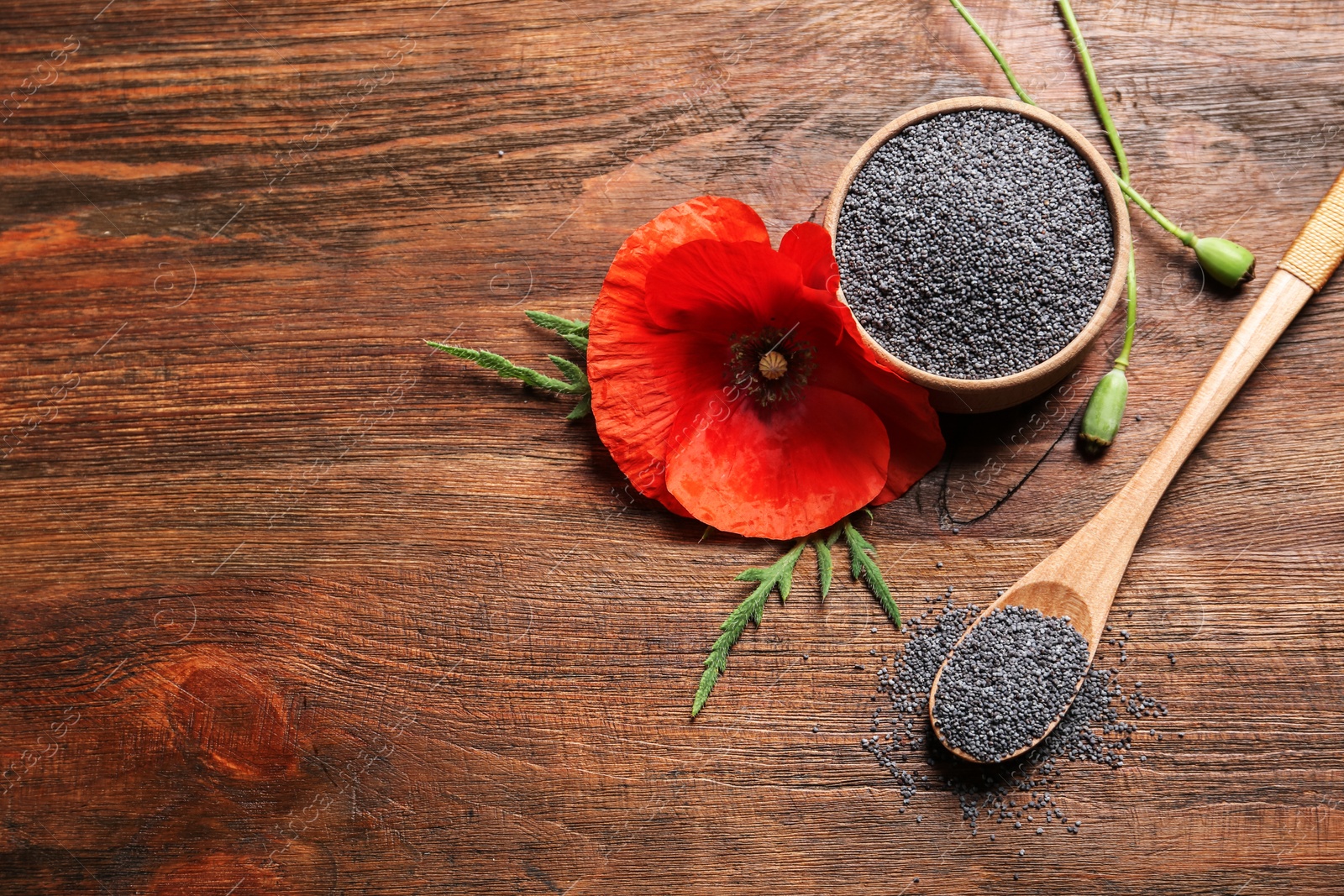 Photo of Flat lay composition with poppy seeds and flower on wooden table, space for text