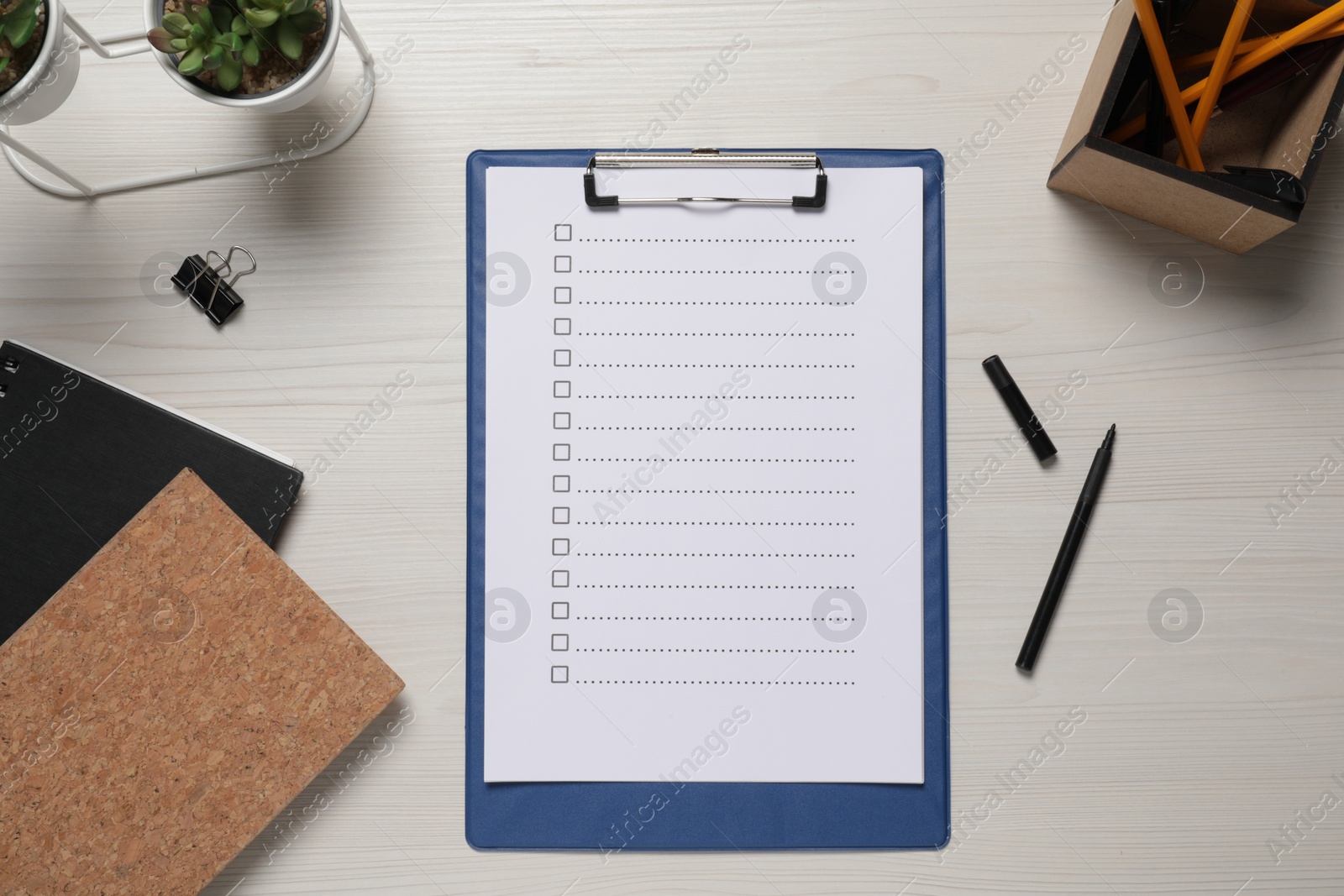 Photo of Clipboard with checkboxes, plant and office stationery on white wooden table, flat lay. Checklist