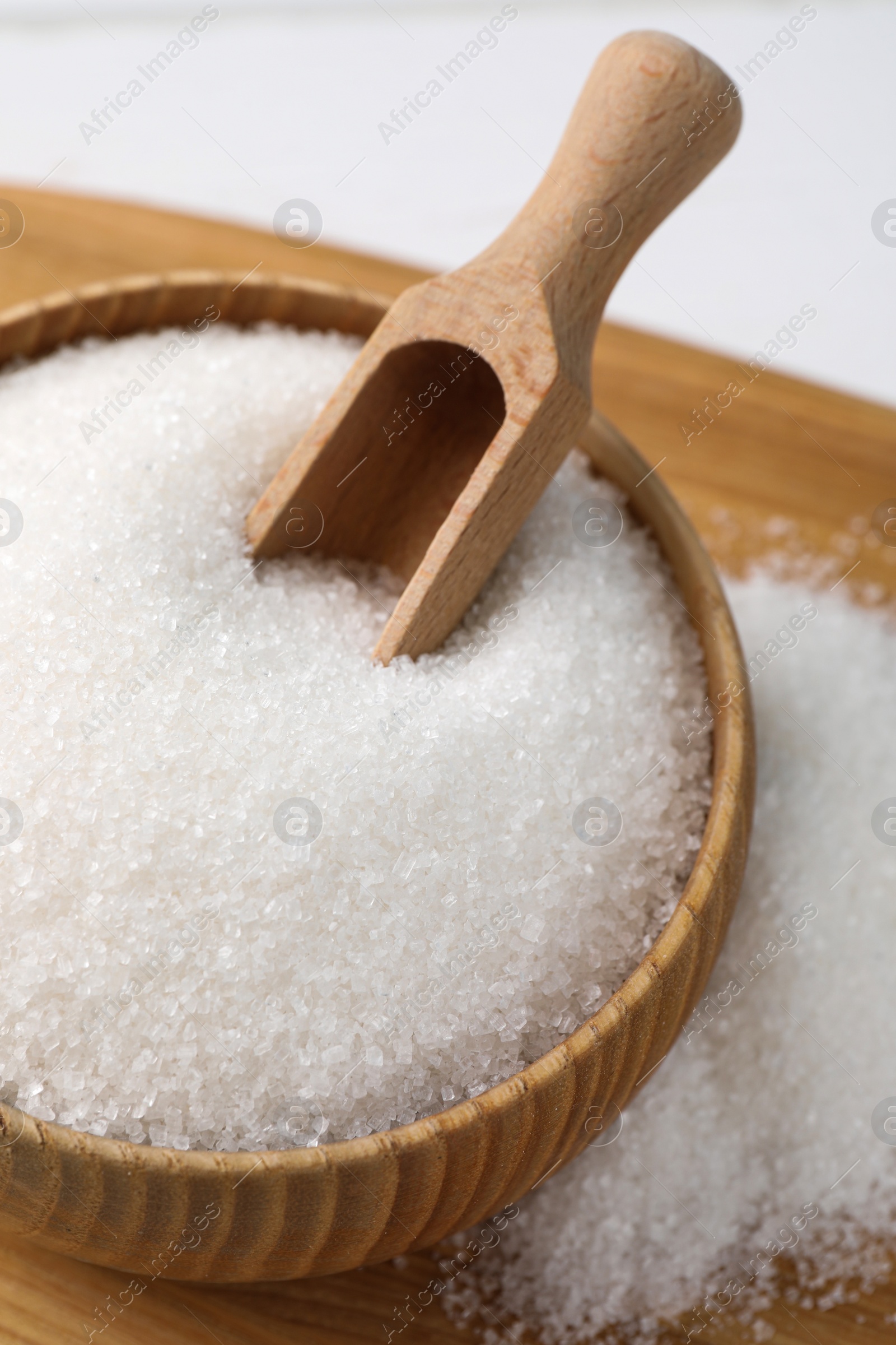 Photo of Wooden bowl with granulated sugar and scoop on table, above view