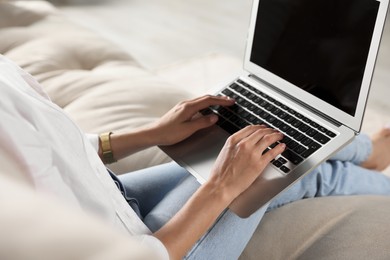 Photo of Young woman working with laptop on sofa, closeup