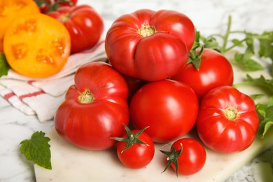 Photo of Pile of different ripe tomatoes on white table