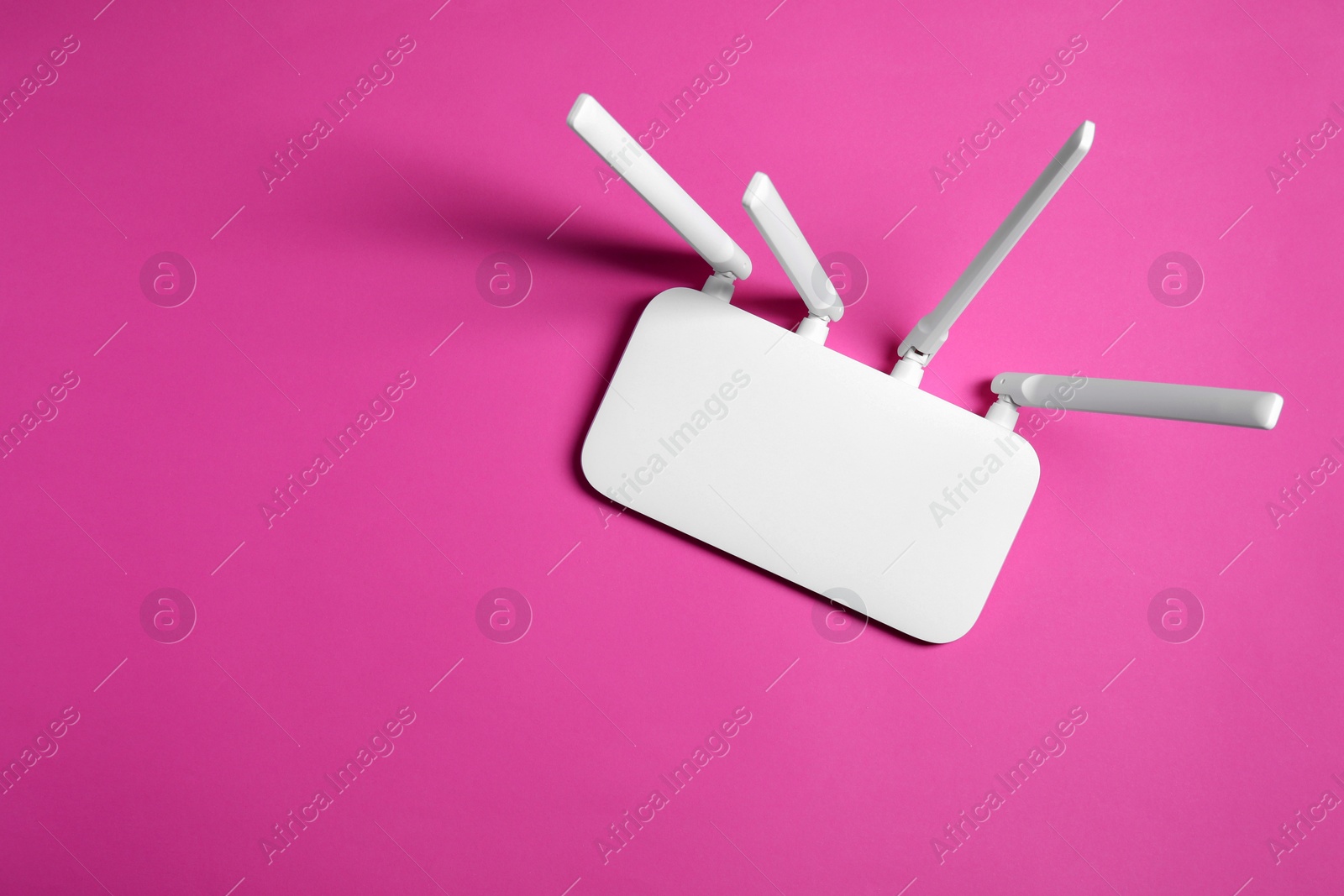 Photo of New white Wi-Fi router on pink background, top view. Space for text