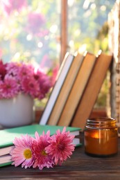 Photo of Book with beautiful chrysanthemum flowers as bookmark and candle on wooden table