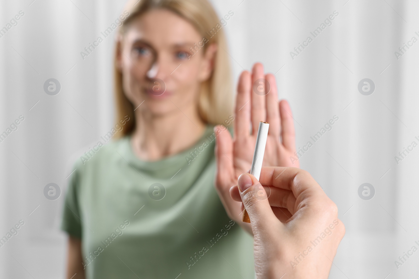 Photo of Woman refusing cigarette on light background, selective focus. Quitting smoking concept