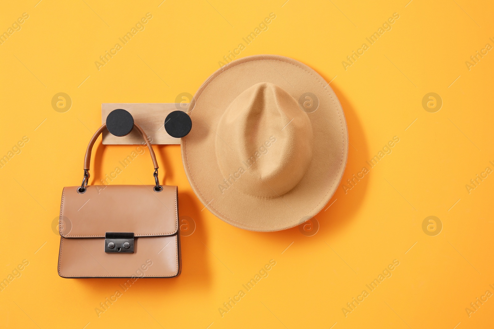 Photo of Rack with brown hat and bag on orange wall