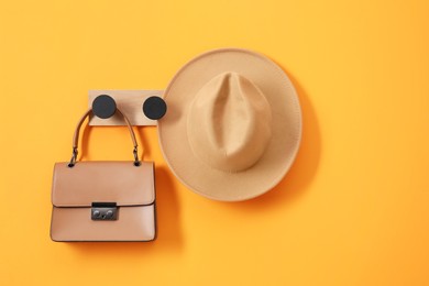 Photo of Rack with brown hat and bag on orange wall