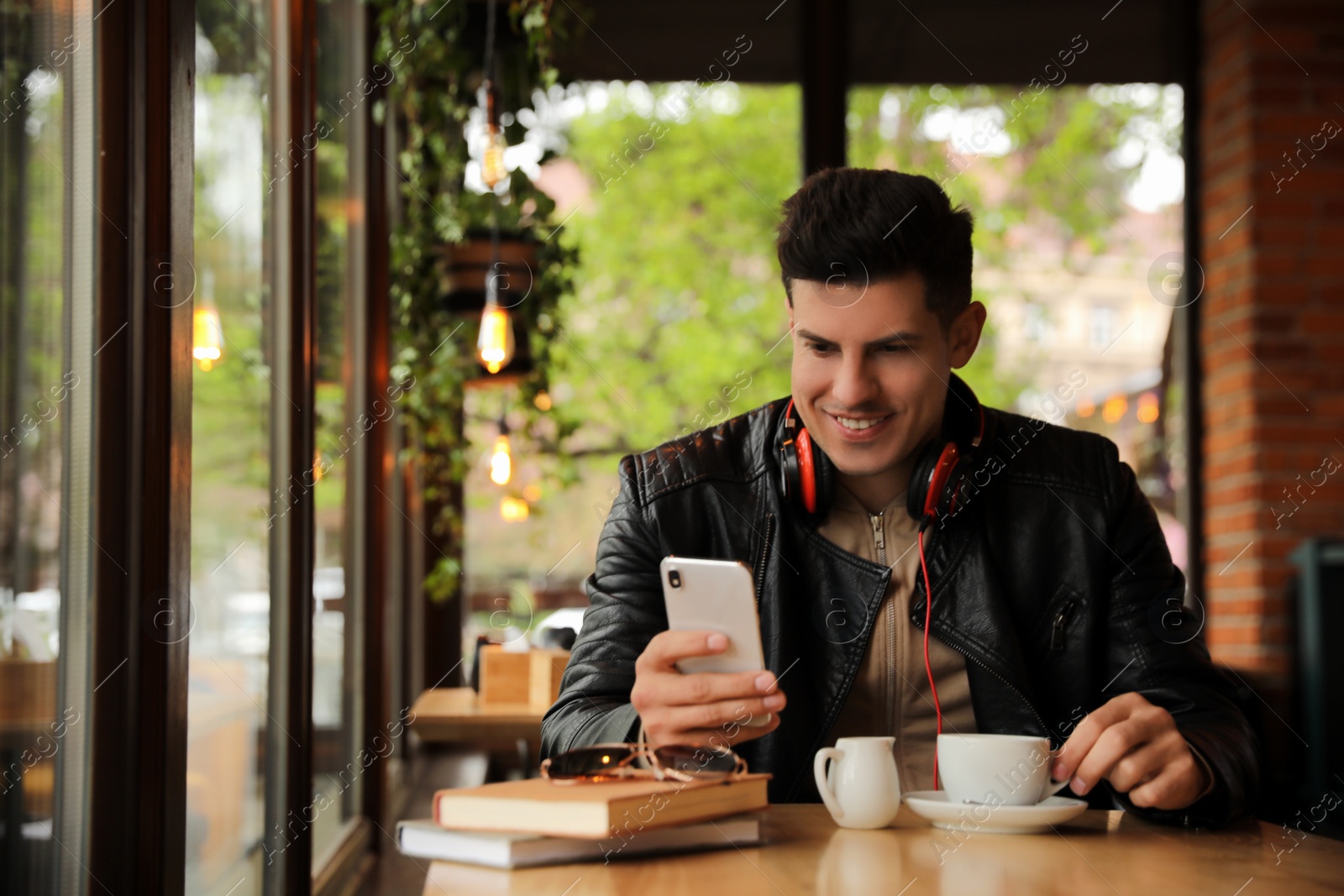 Photo of Man with headphones and smartphone at table in cafe