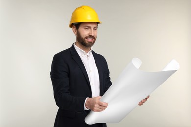 Photo of Architect in hard hat with draft on gray background