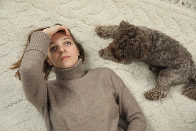 Photo of Sad young woman and her dog lying on floor at home