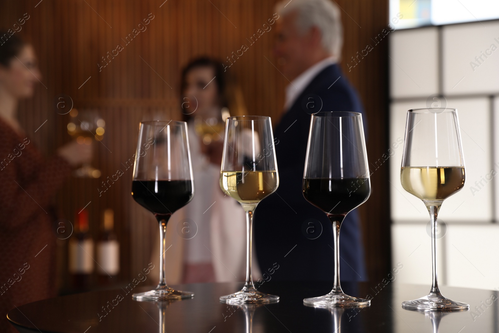 Photo of Glasses of different wines on table against blurred background