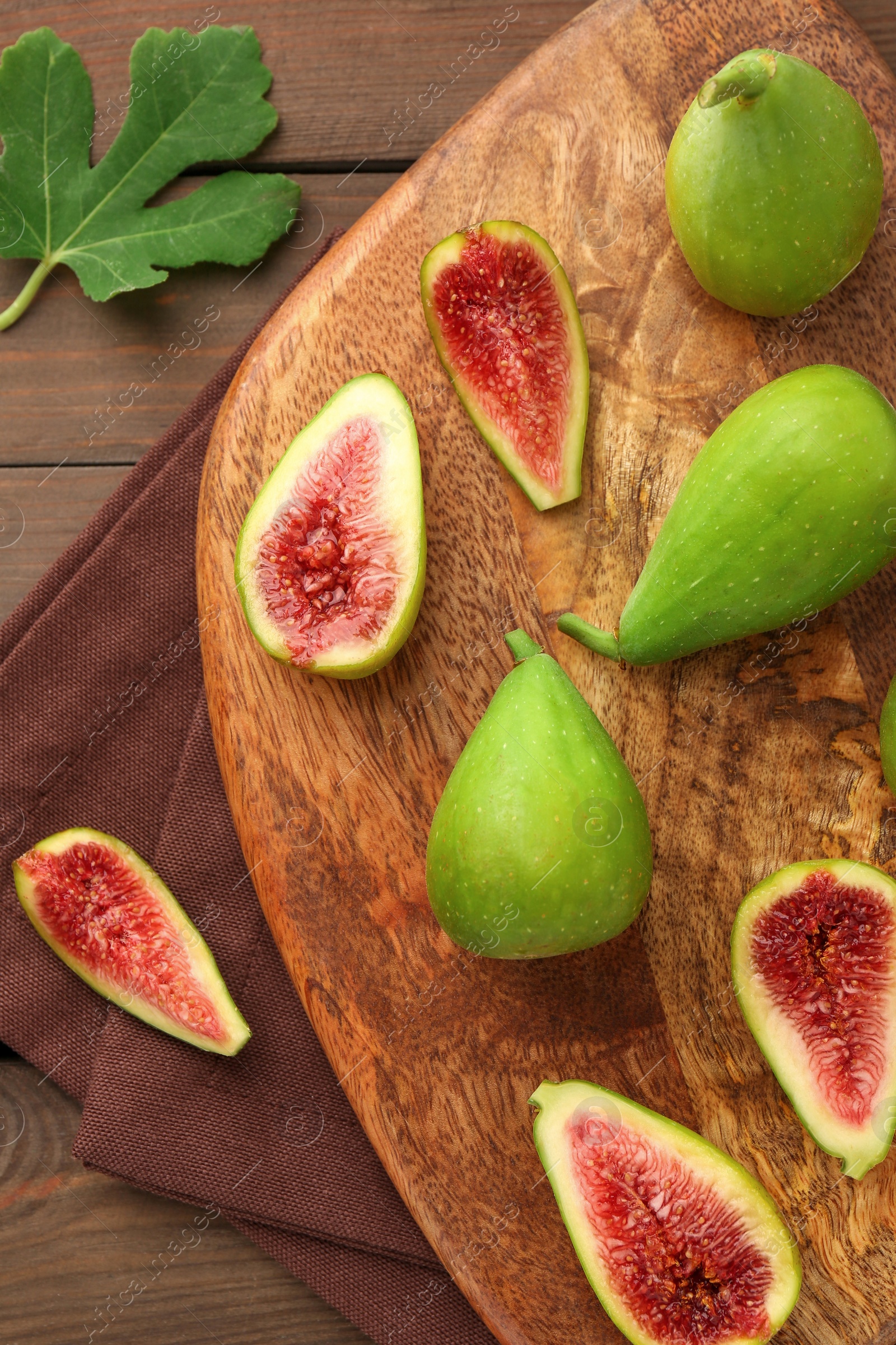 Photo of Cut and whole green figs on wooden table, flat lay