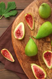 Cut and whole green figs on wooden table, flat lay