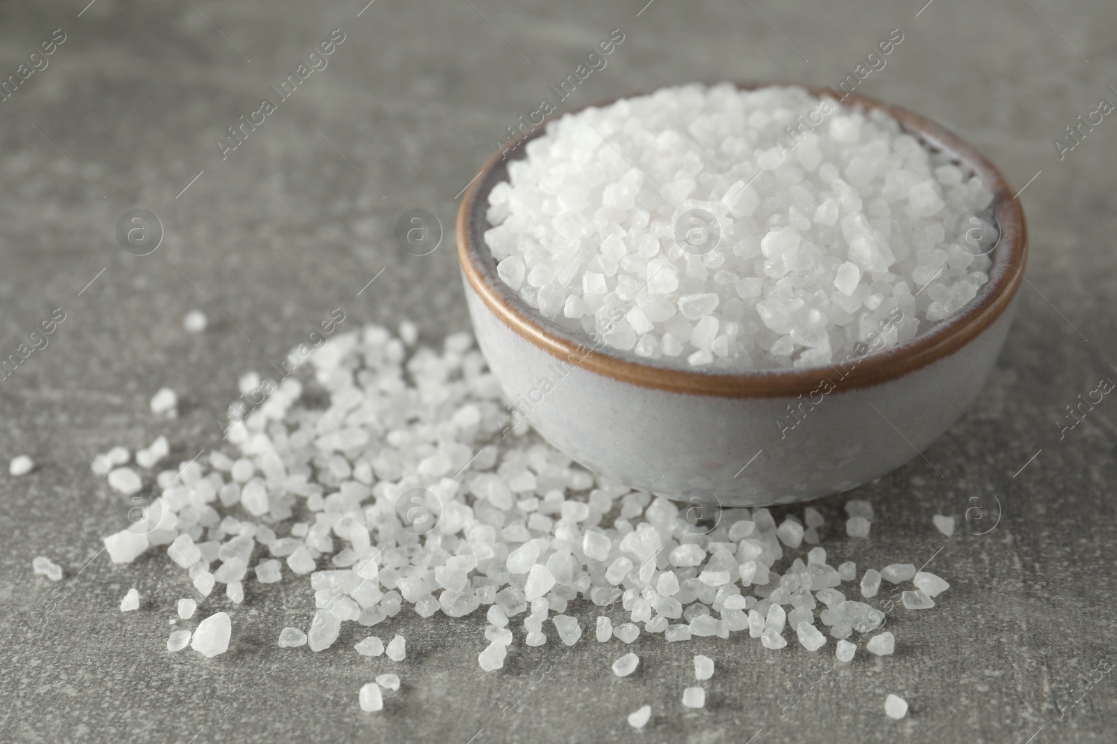 Photo of Bowl of natural sea salt on grey table
