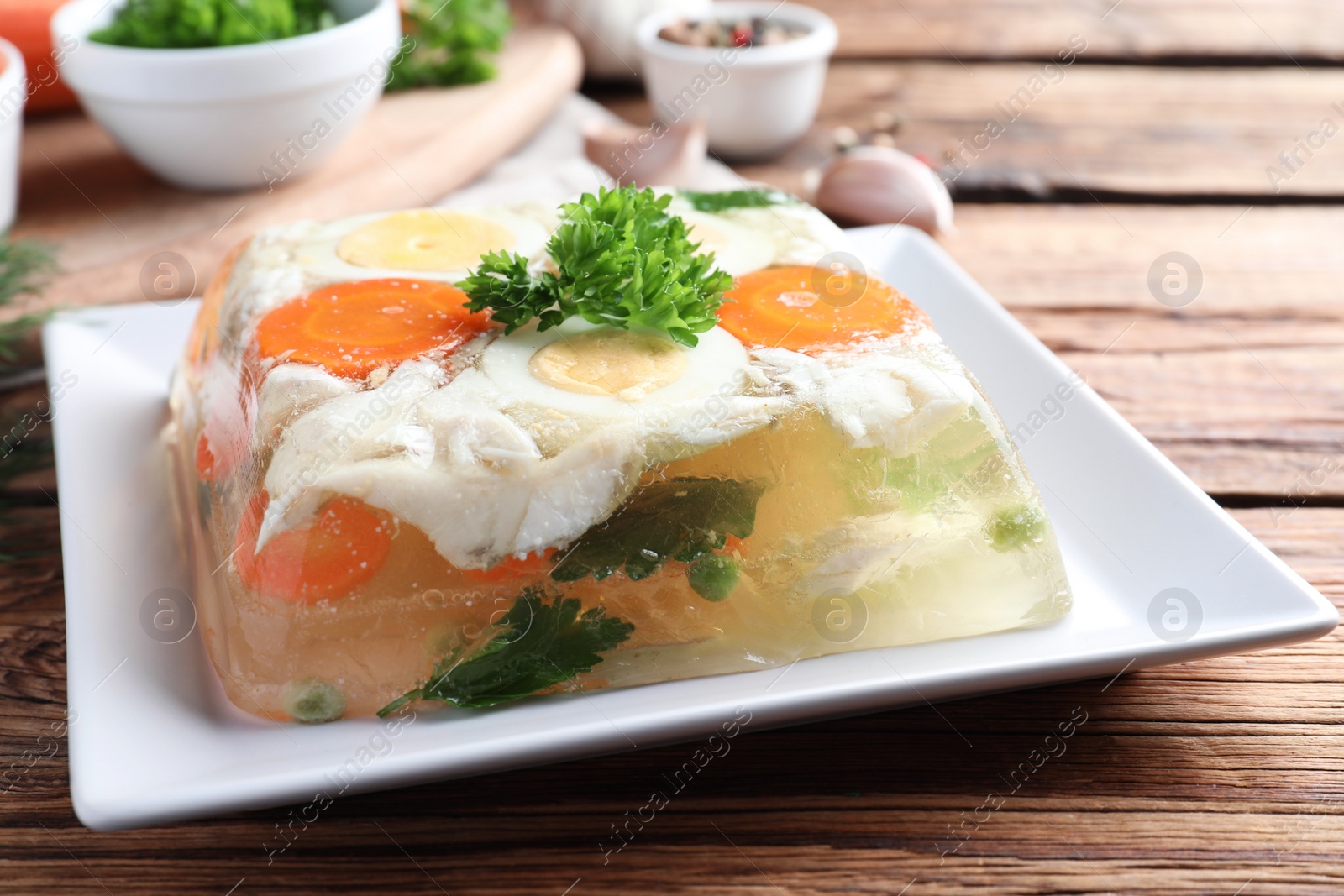 Photo of Delicious fish aspic served on wooden table, closeup