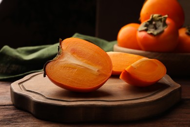Photo of Delicious ripe juicy persimmons on wooden table