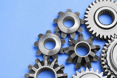 Photo of Different stainless steel gears on light blue background, above view. Space for text