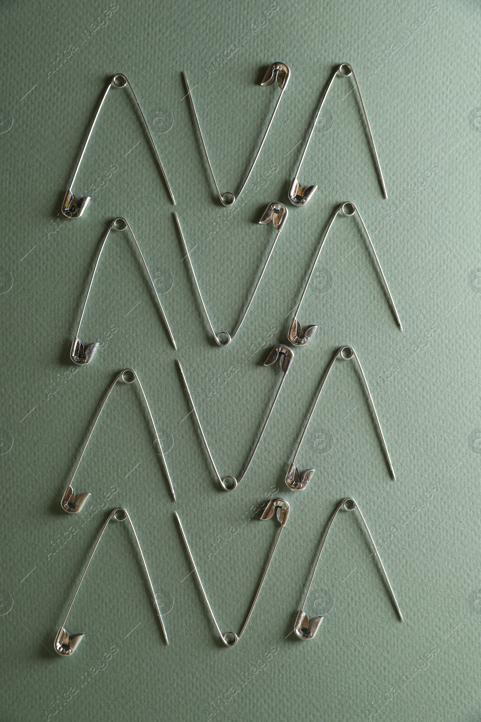 Photo of Many safety pins on green background, flat lay