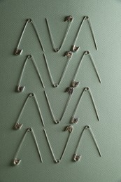 Photo of Many safety pins on green background, flat lay