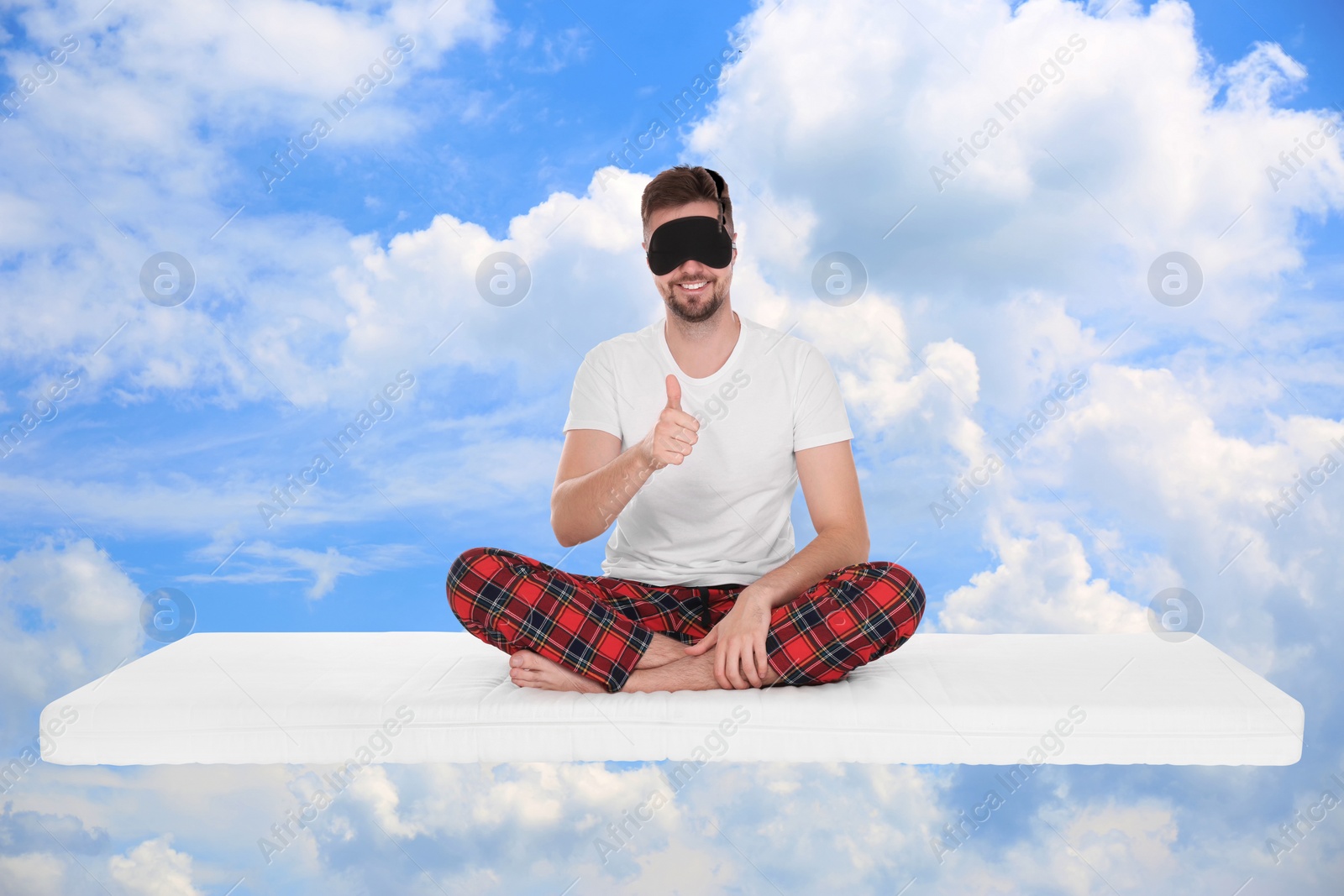 Image of Healthy sleep. Man showing thumbs up on comfortable mattress in blue sky