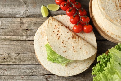 Photo of Tasty homemade tortillas, tomatoes, lime and lettuce on wooden table, top view. Space for text