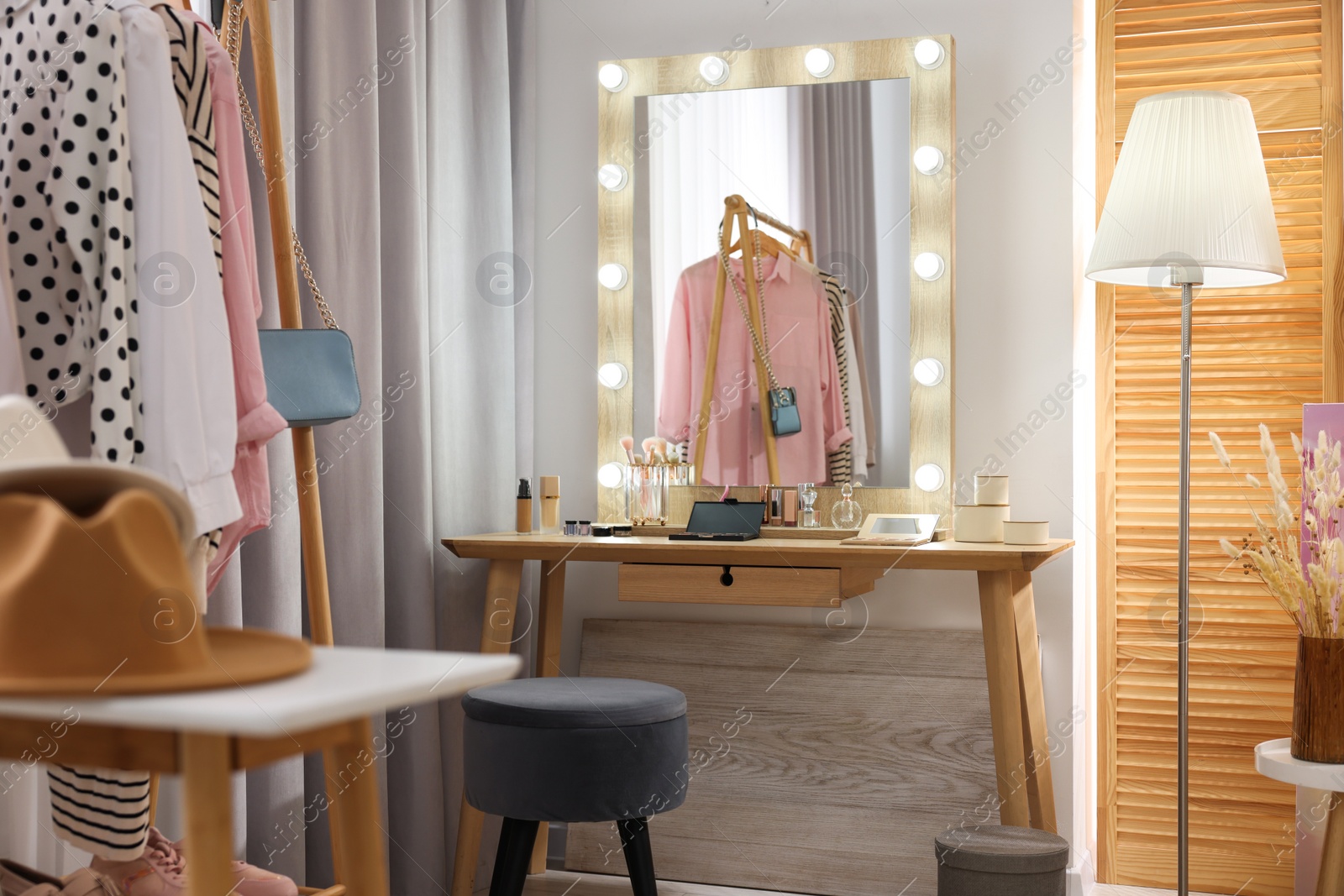 Photo of Makeup room. Stylish wooden dressing table with mirror and chair indoors