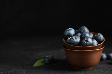 Fresh ripe blueberries in bowl on dark table. Space for text