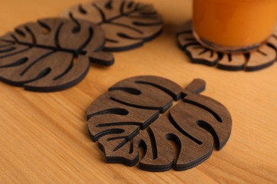 Photo of Many leaf shaped wooden cup coasters on table