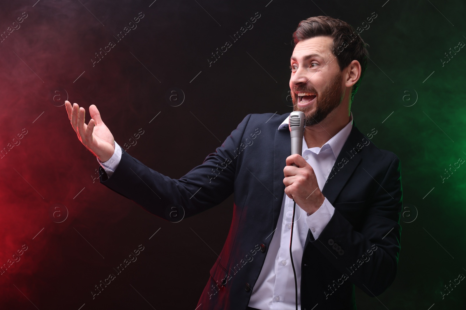 Photo of Emotional man with microphone singing in color lights