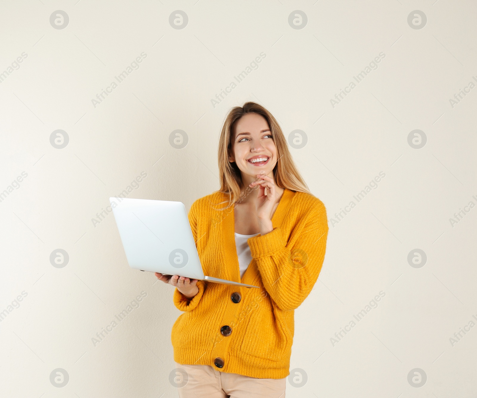 Photo of Portrait of young woman in casual outfit with laptop on light background. Space for text