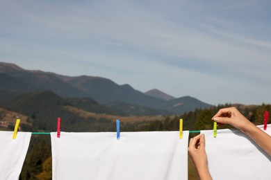 Woman putting clothes pins on laundry line outdoors, closeup. Space for text